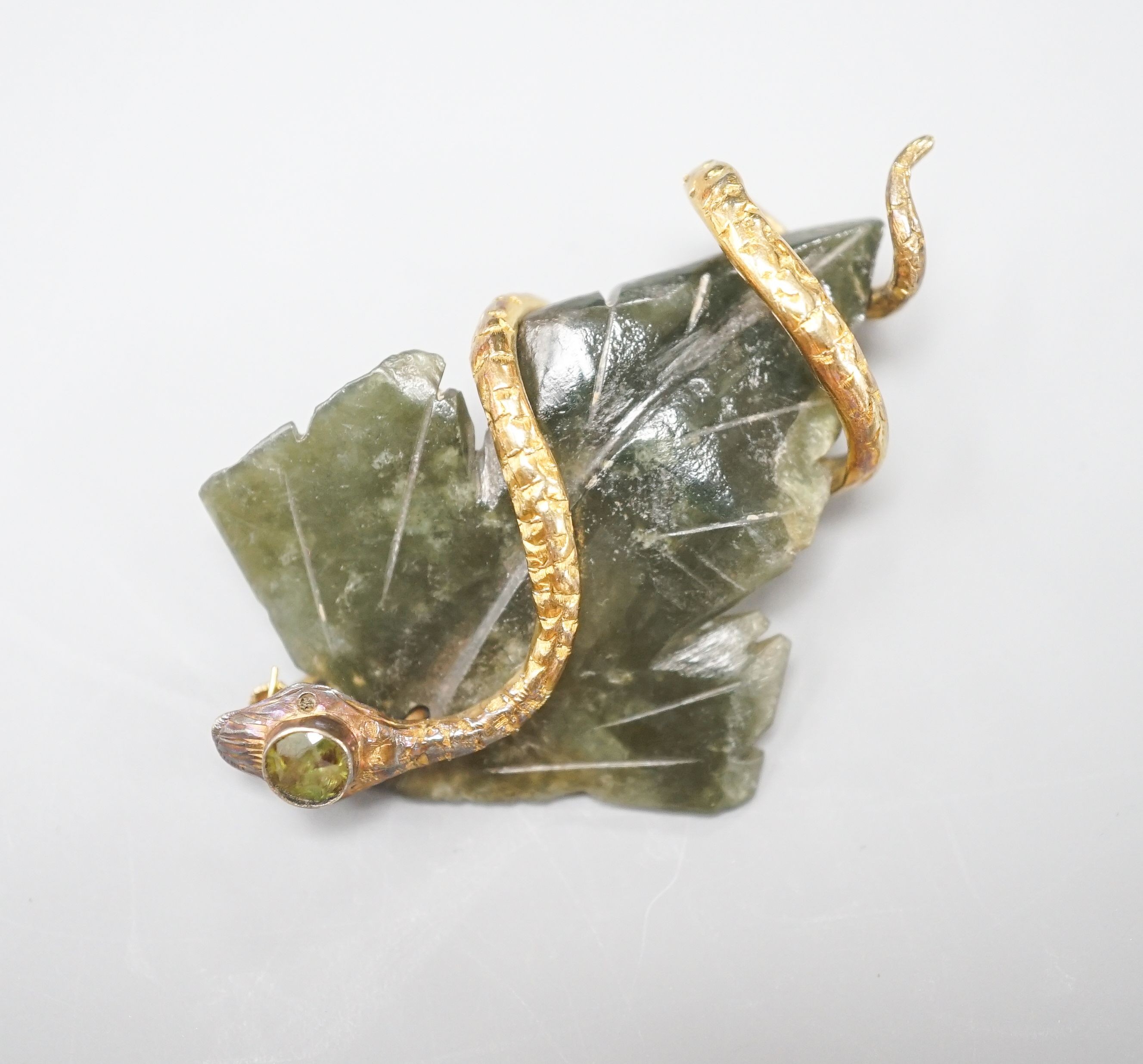 A continental yellow metal, garnet and nephrite set brooch, modelled as a leaf entwined with serpent, 56mm, gross weight 14 grams.